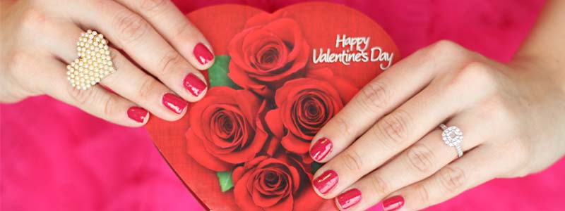hands with painted nails holding a valentines box of chocolates